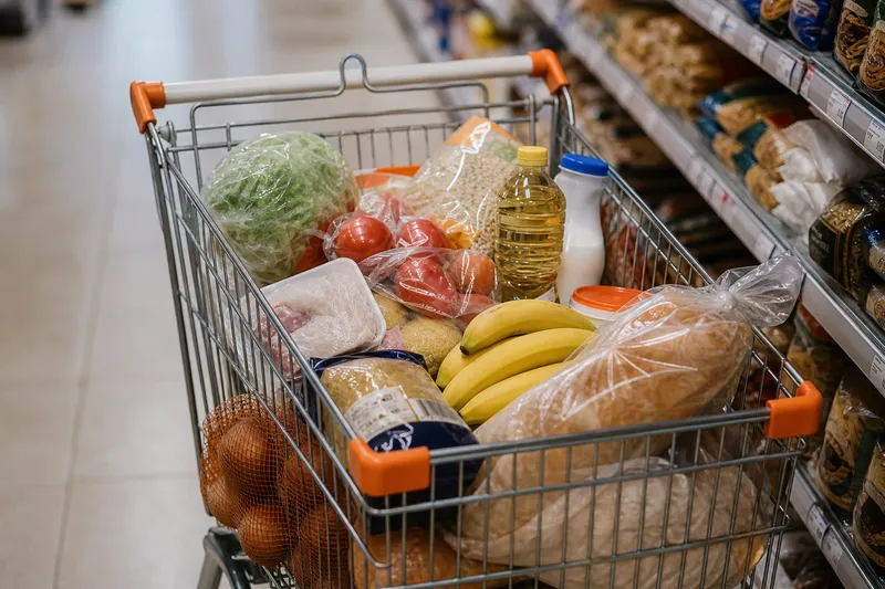 Полная продуктовая тележка с овощами, фруктами, хлебом и товарами в турецком супермаркете